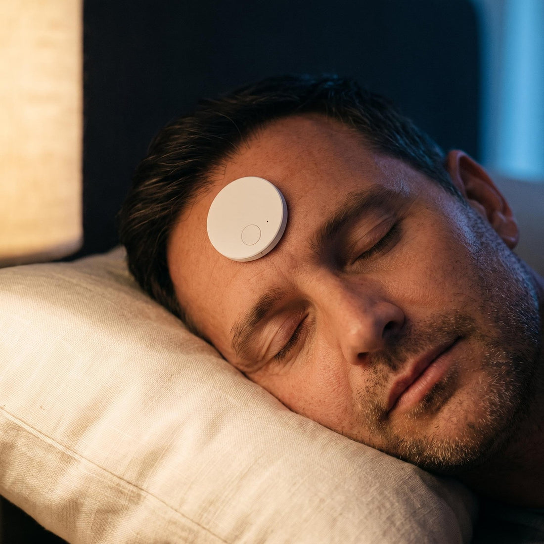 Close-up of the flat white Dusk trainer adhered flush to a sleeper's forehead at night