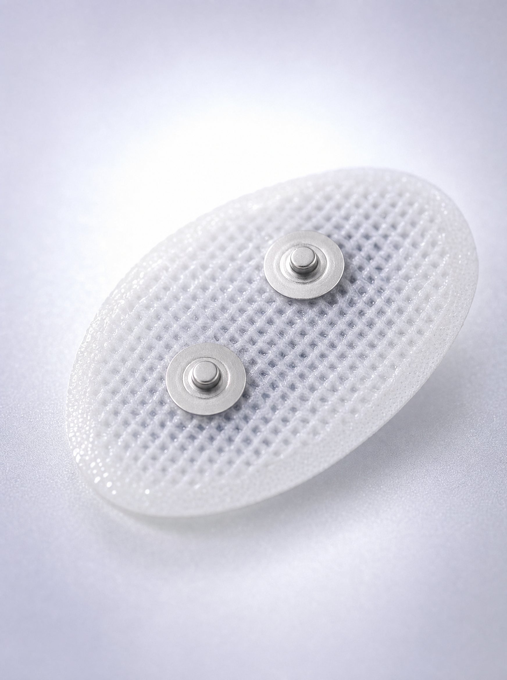 Macro of a FYROST Hush gel pad, showing the mesh face and twin snap studs